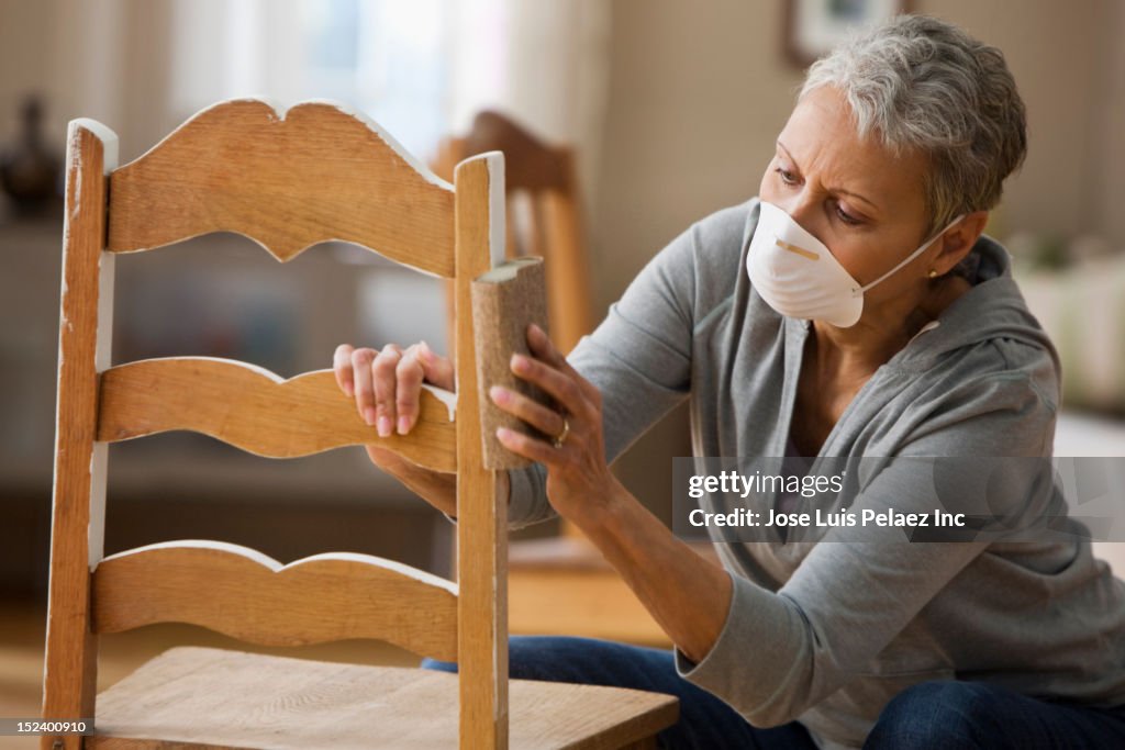 Mixed race woman refinishing chair