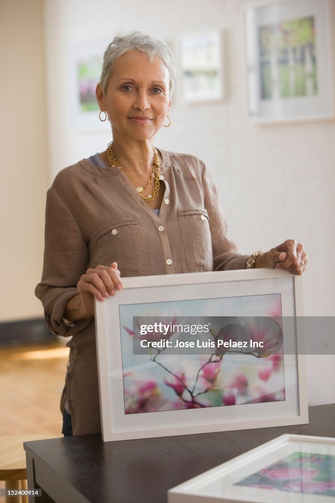 Mixed race woman holding picture of flowers