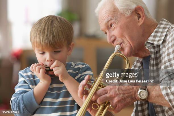 caucasian grandfather and grandson playing instruments together - harmonica stock pictures, royalty-free photos & images