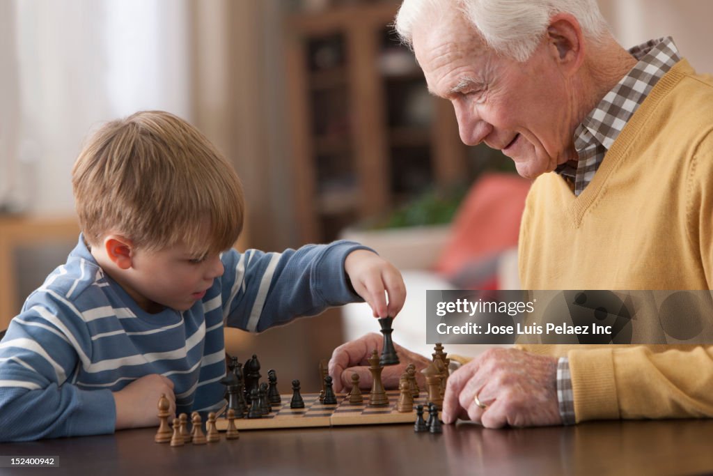 Caucasian grandfather and grandson playing chess