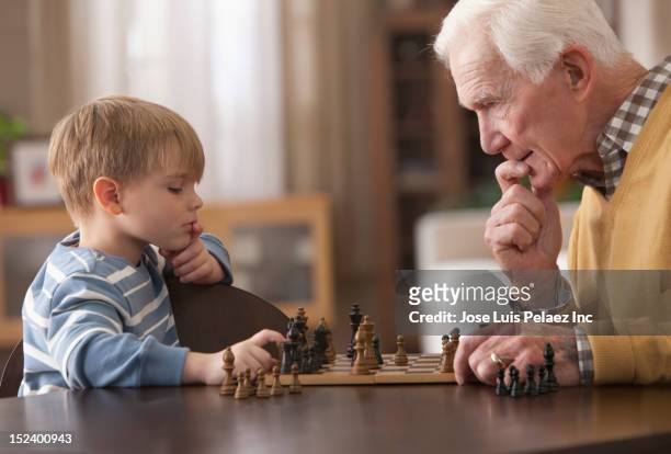 caucasian grandfather and grandson playing chess - playing chess stockfoto's en -beelden