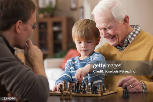 caucasian grandfather and grandson playing chess - kids playing chess stock pictures, royalty-free photos & images