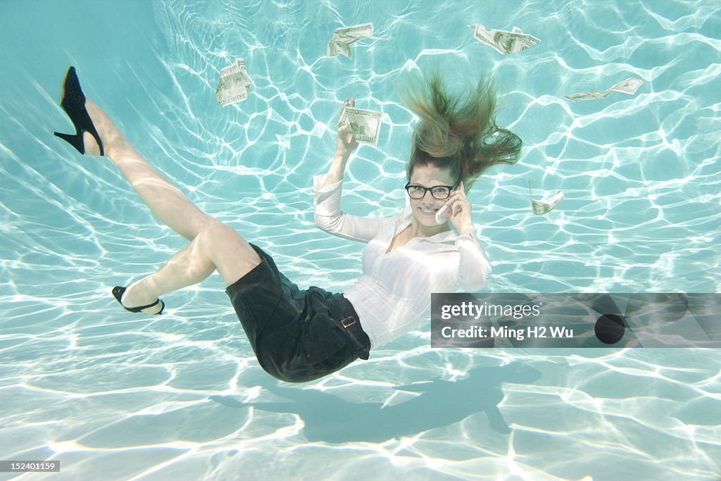 Caucasian businesswoman reaching for money underwater