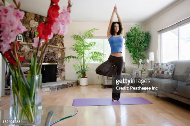 hispanic woman practicing yoga in living room - tree position stock pictures, royalty-free photos & images