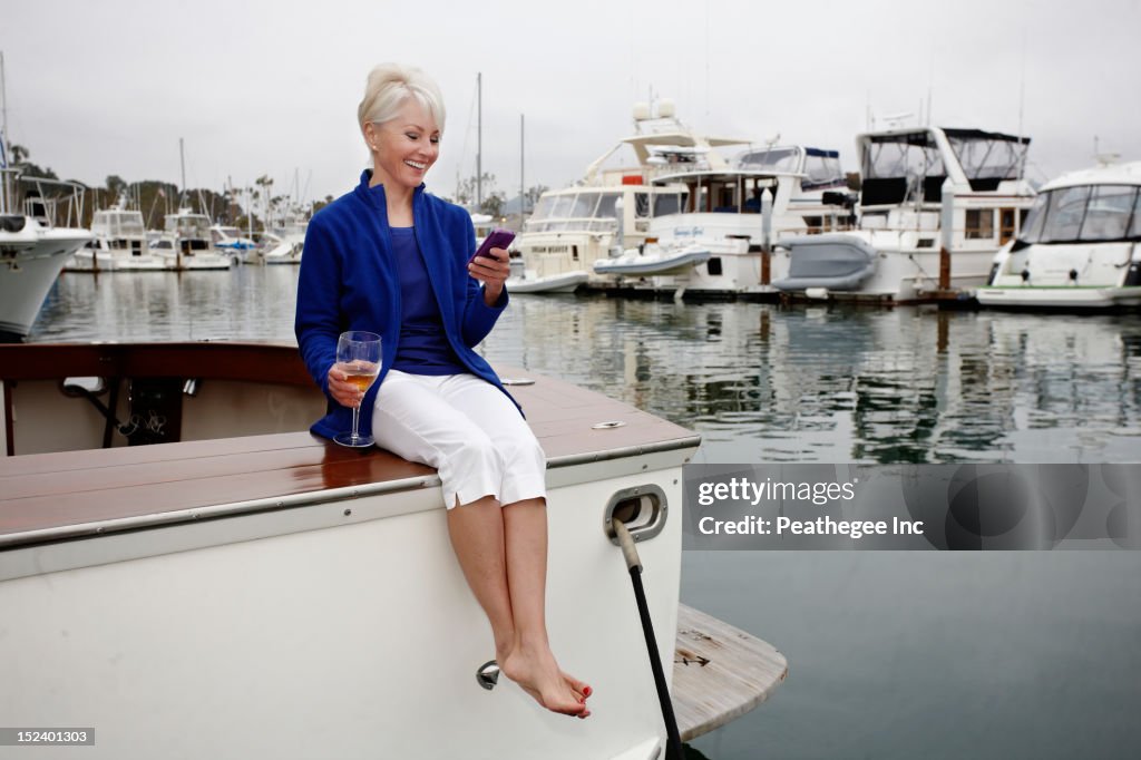Woman sitting on boat text messaging on cell phone