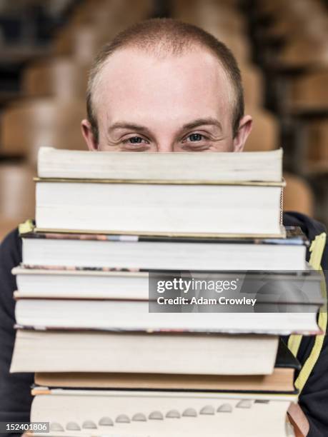 caucasian student holding stack of books - college student holding books stockfoto's en -beelden