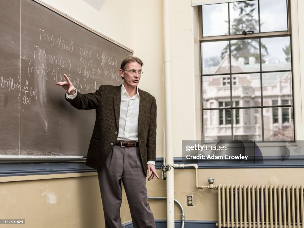 Caucasian teacher writing on blackboard