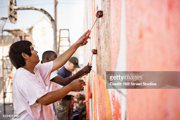 volunteers painting wall - volunteer building stock pictures, royalty-free photos & images