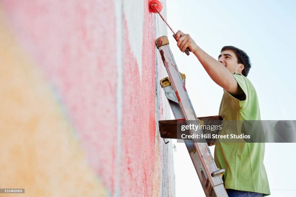 Mixed race man painting wall