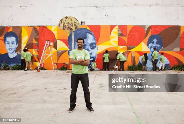 volunteers painting wall - kids standing crossed arms stock-fotos und bilder