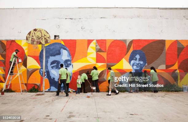volunteers painting wall together - creative people outside imagens e fotografias de stock
