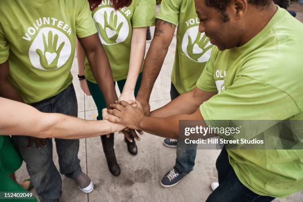 volunteers holding hands in circle - voluntario fotografías e imágenes de stock