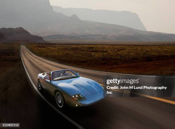 sports car on remote highway - sportwagen stock-fotos und bilder