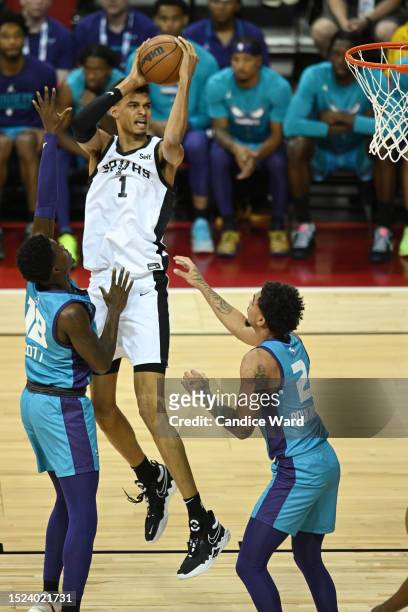 Victor Wembanyama of the San Antonio Spurs shoots the ball between Tre Scott and James Bouknight of the Charlotte Hornets during the first quarter at...