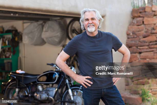 caucasian man in driveway with motorcycle - mann stolz stock-fotos und bilder