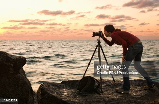 mixed race woman using camera near ocean - tripod stock pictures, royalty-free photos & images