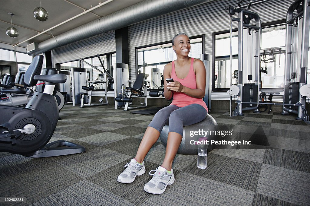 African American woman text messaging on cell phone in health club