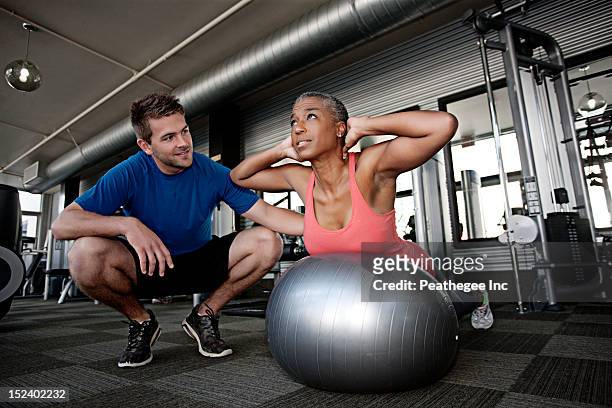personal trainer helping woman in health club - pilates ball man stock-fotos und bilder