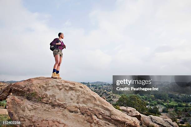 black hiker standing on rock in remote area - mountain side stock pictures, royalty-free photos & images