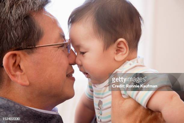 grandfather giving chinese grandson eskimo kiss - nuzzling foto e immagini stock