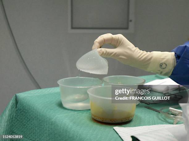 Nurse holds a breast implant during an operation, 04 November 2003 in a plastic surgery clinic in Paris. Une infirmière prend un implant mammaire...