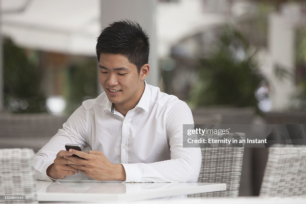 Asian Businessman sitting at cafe with smartphone