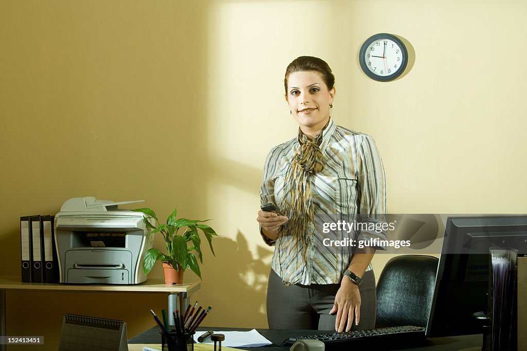 Businesswoman holding cell phone in office