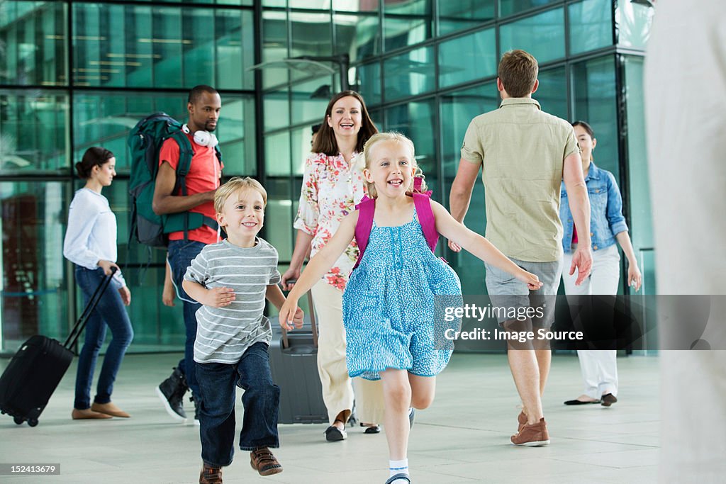 Excited children running on airport concourse