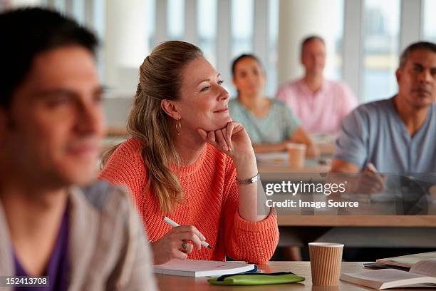 mature students in class, woman with hand on chin - mature student stock pictures, royalty-free photos & images