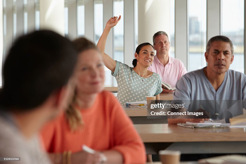 Mature students in class, woman with hand up