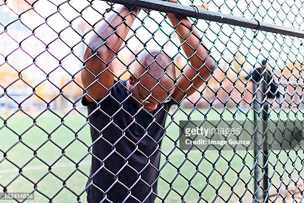 man behind a chain link fence - segregation stock pictures, royalty-free photos & images