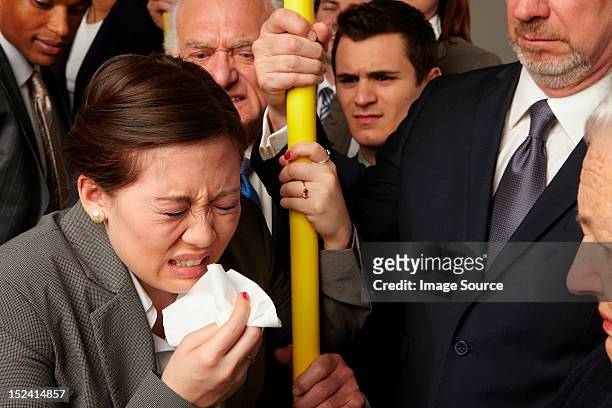 businesswoman sneezing on subway train - busy tube stock-fotos und bilder