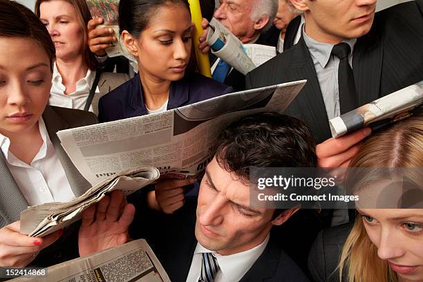 businesspeople reading newspapers on crowded train - atestado fotografías e imágenes de stock