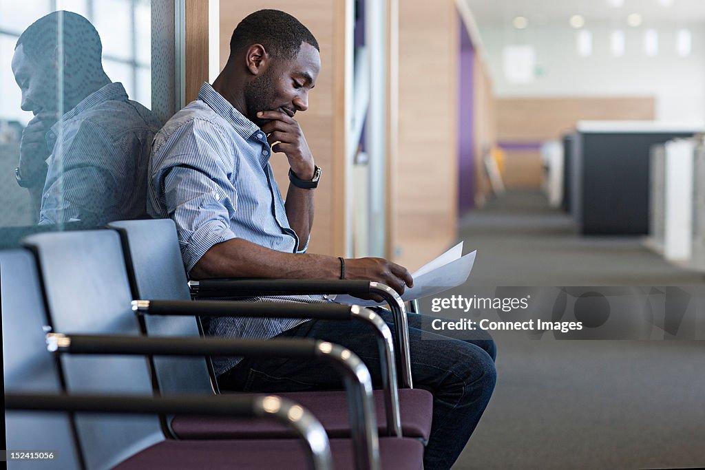 Man sitting on chair reading document