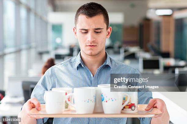 nervous looking man carrying tray of mugs - holding cup stock pictures, royalty-free photos & images