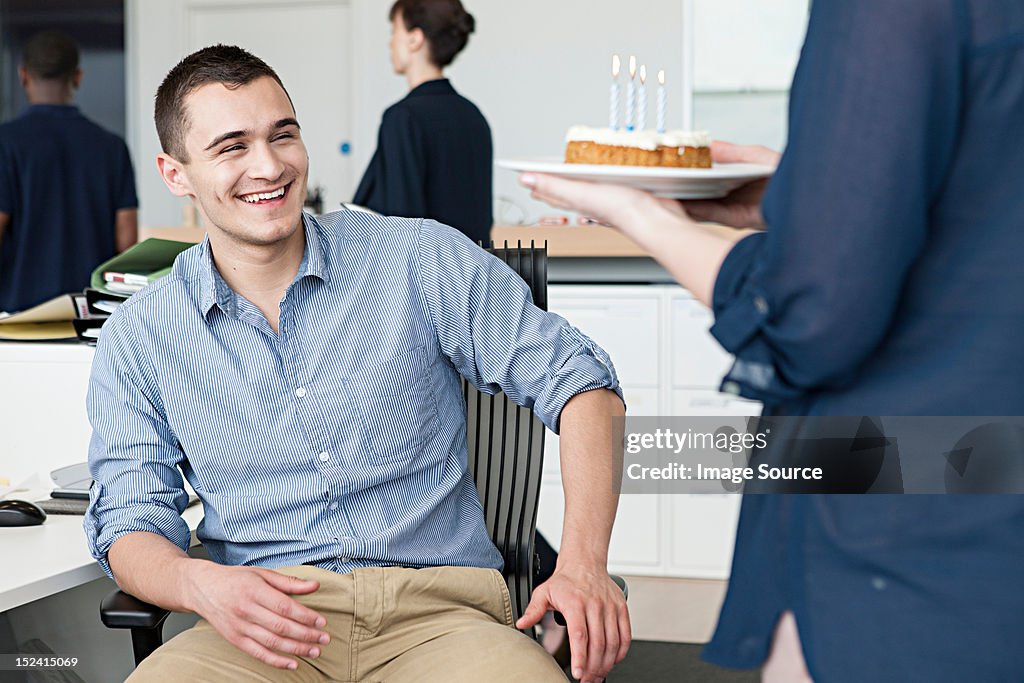 Woman bringing male colleague birthday cake in office