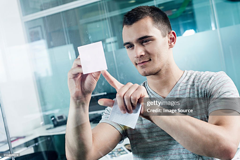 Man sticking adhesive note to window