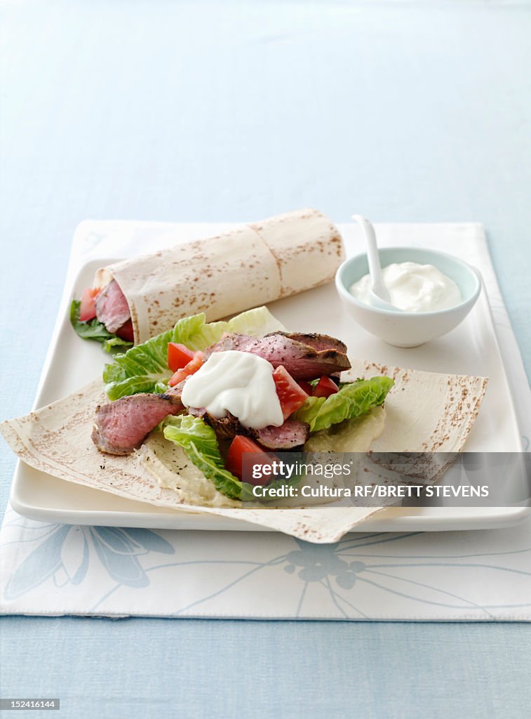 Plate of meat, salad and flatbread wrap