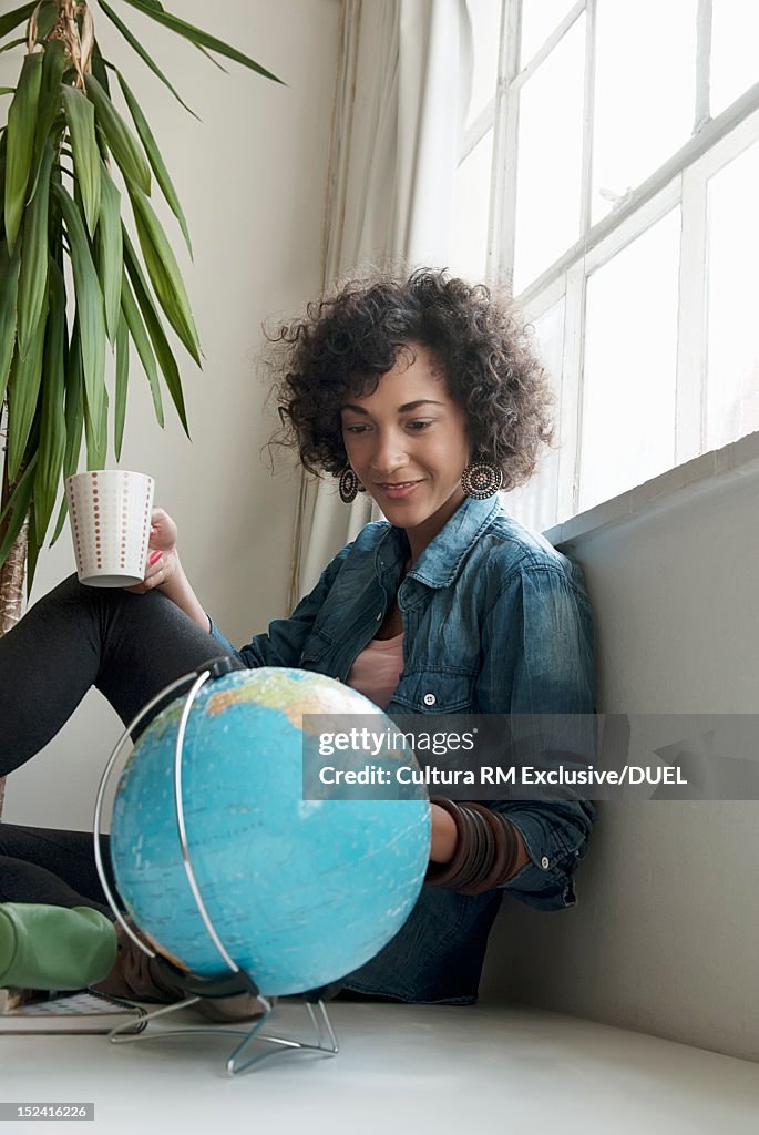 Smiling woman examining globe