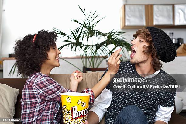 woman feeding boyfriend popcorn - attraper photos et images de collection