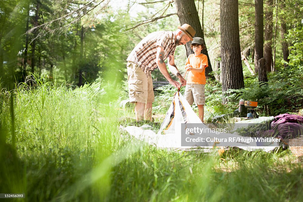 Father and son pitching tent in forest