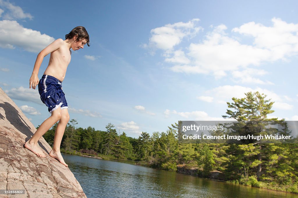 Boy climbing on rock by river