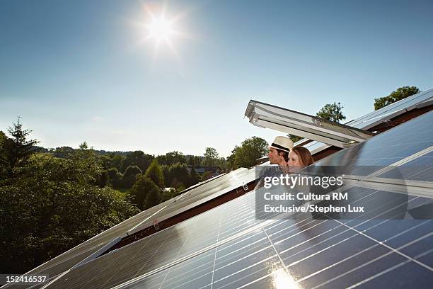 couple peering out of solar panel roof - zonnepanelen stockfoto's en -beelden