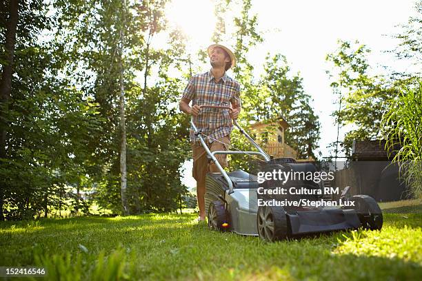 man mowing backyard lawn - lawnmower stock-fotos und bilder