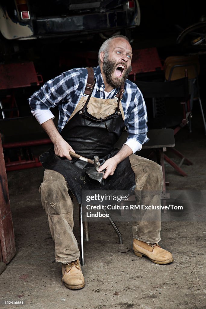 Mechanic smashing his thumb in garage