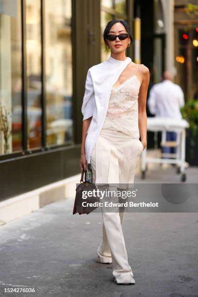 Chriselle Lim wears black sunglasses from Fendi, gold embossed cut-out logo earrings from Fendi, a white wool scarf, a white embossed lace pattern...