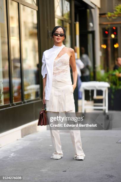 Chriselle Lim wears black sunglasses from Fendi, gold embossed cut-out logo earrings from Fendi, a white wool scarf, a white embossed lace pattern...