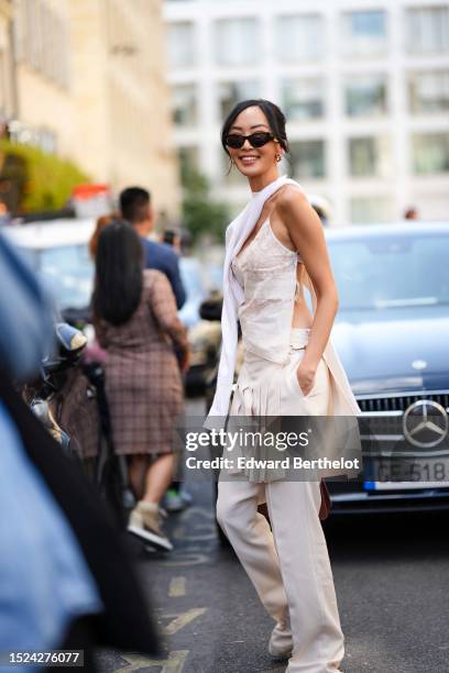 Chriselle Lim wears black sunglasses from Fendi, gold embossed cut-out logo earrings from Fendi, a white wool scarf, a white embossed lace pattern...