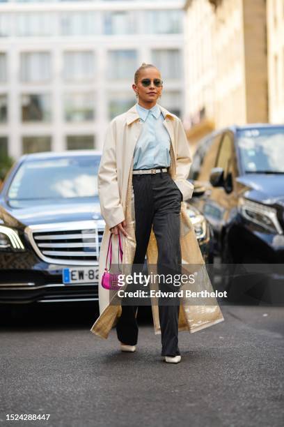 Caroline Daur wears black aviator sunglasses, gold earrings from Tiffany, a pale blue shirt from Fendi, a white latte / pale yellow with embroidered...