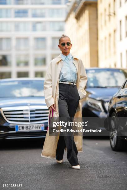 Caroline Daur wears black aviator sunglasses, gold earrings from Tiffany, a pale blue shirt from Fendi, a white latte / pale yellow with embroidered...